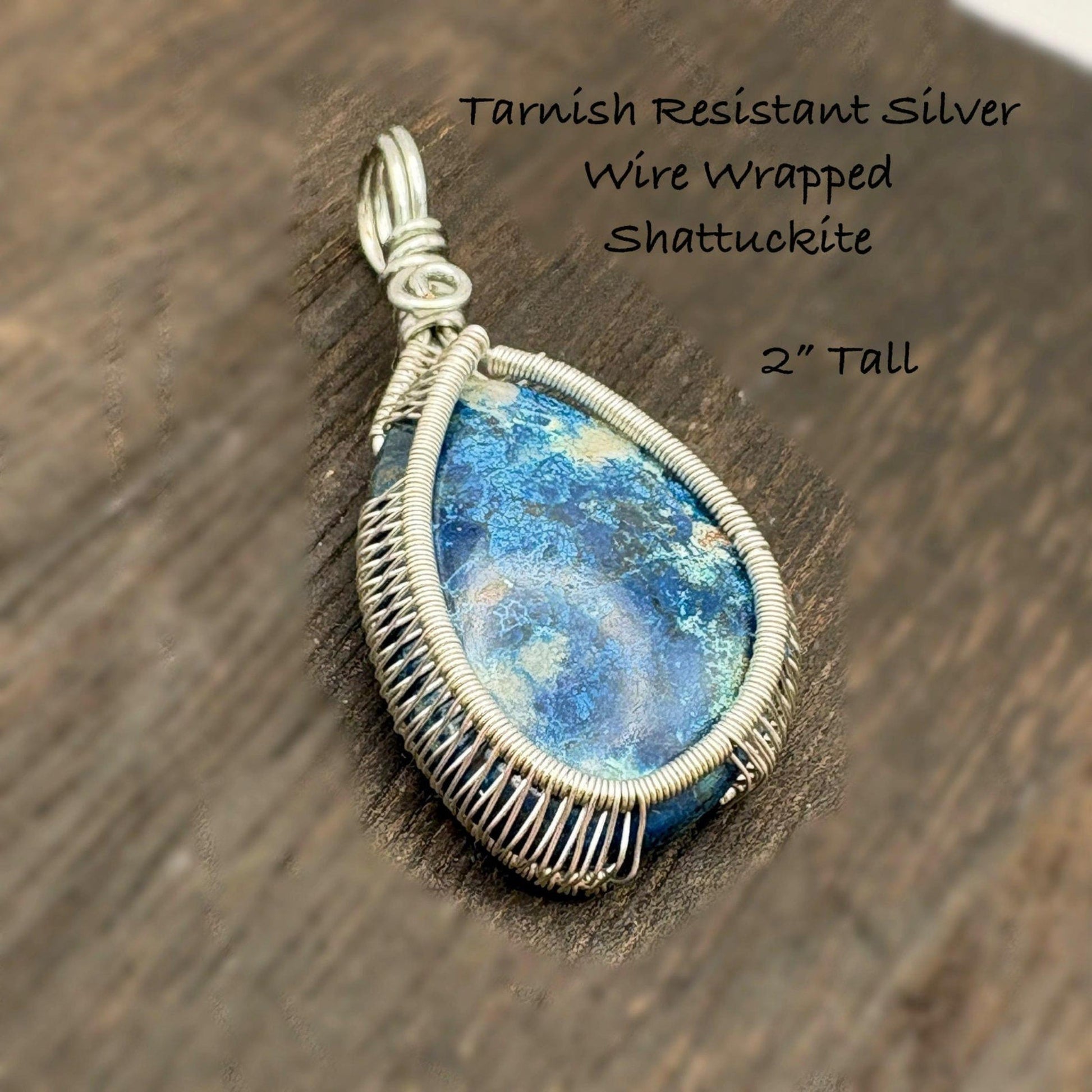 Tarnish resistant silver wire wrapped Shattuckite pendant on a wooden surface