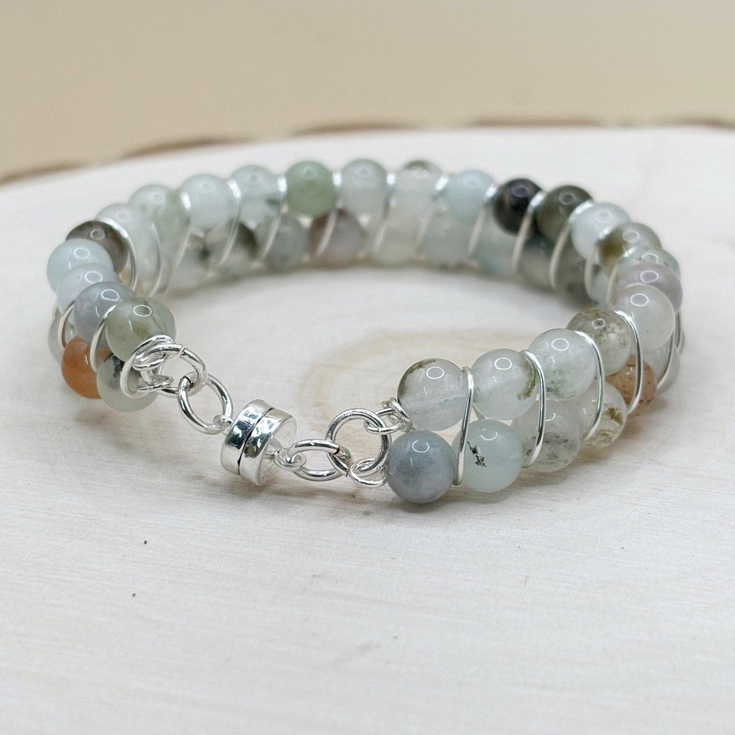 blue stone transparent Beaded bracelet with silver magnetic clasp on a white wood surface
