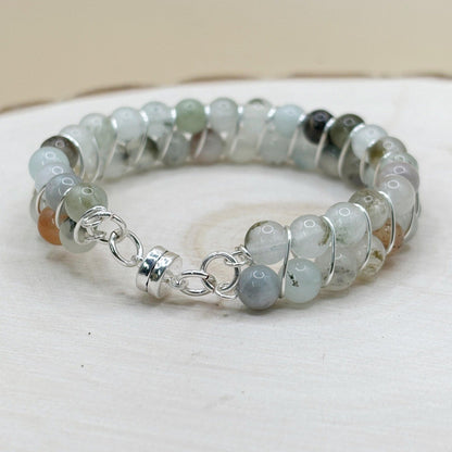 blue stone transparent Beaded bracelet with silver magnetic clasp on a white wood surface