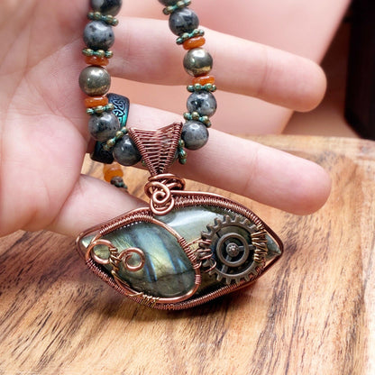 Hand holding a necklace showing size reference of the copper pendant that is hand woven in wire