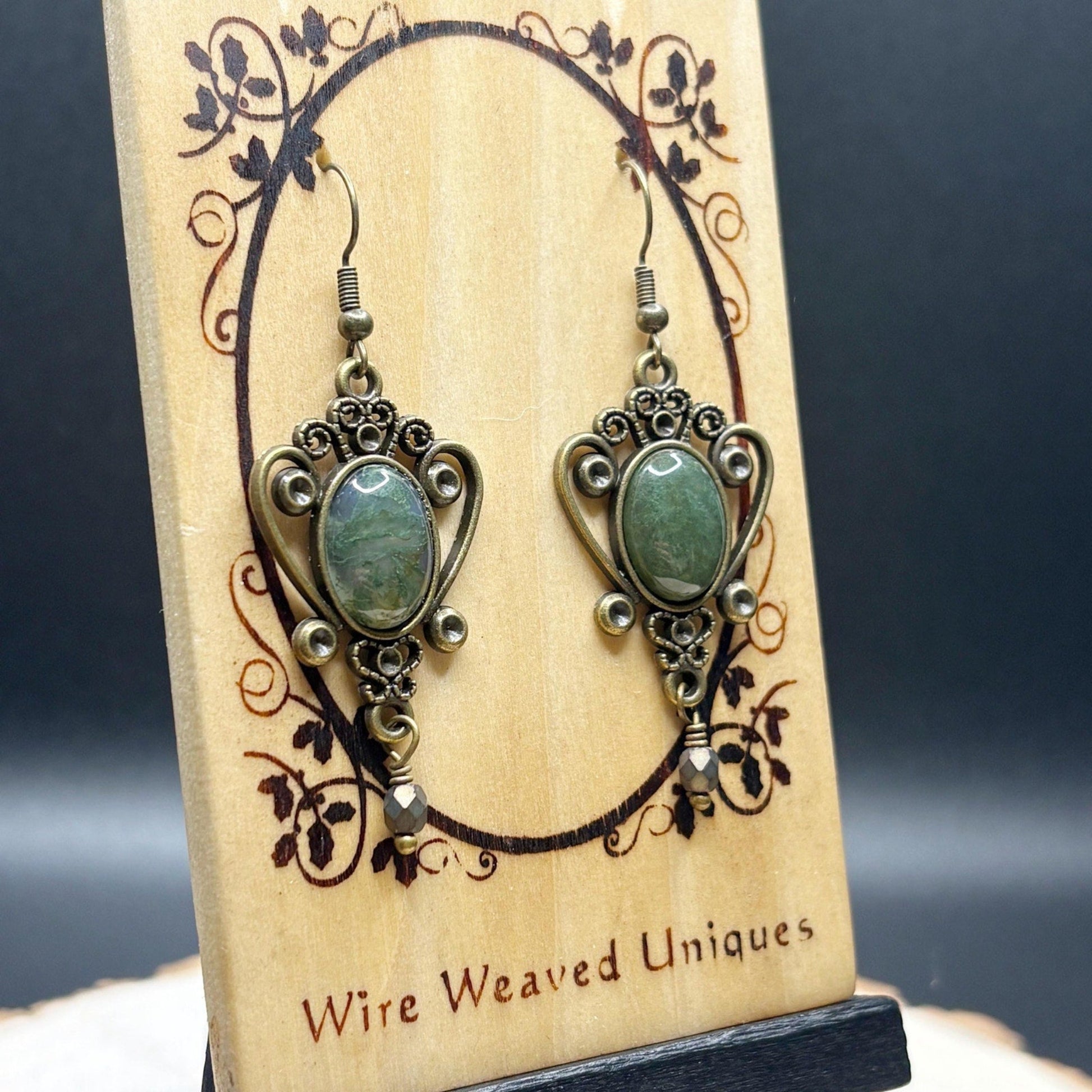 Pair of earrings on a wooden display card with 'Wire Weaved Uniques' branding.