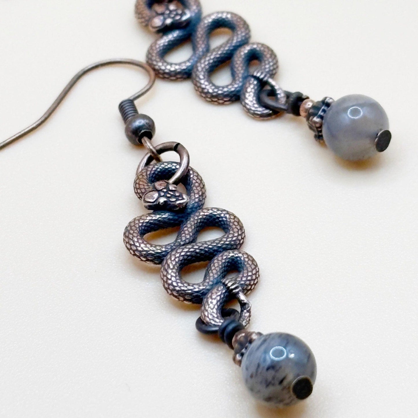 Serpent Snaked earrings with shiny beads on a white background