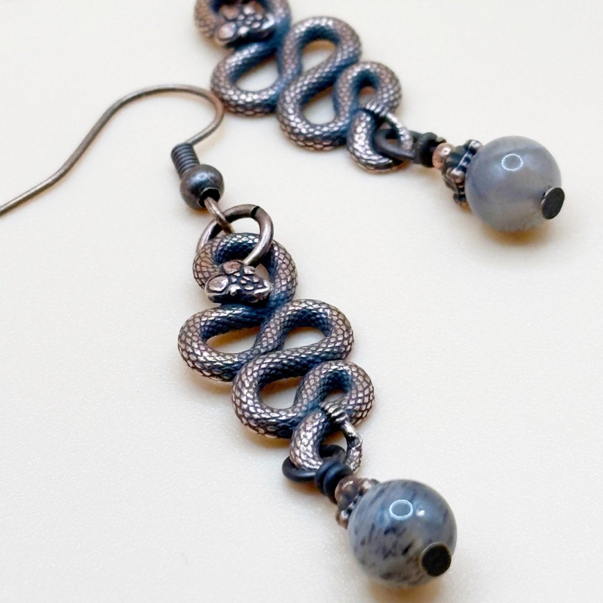 Serpent Snaked earrings with shiny beads on a white background