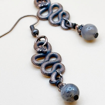 Serpent Snaked earrings with shiny beads on a white background
