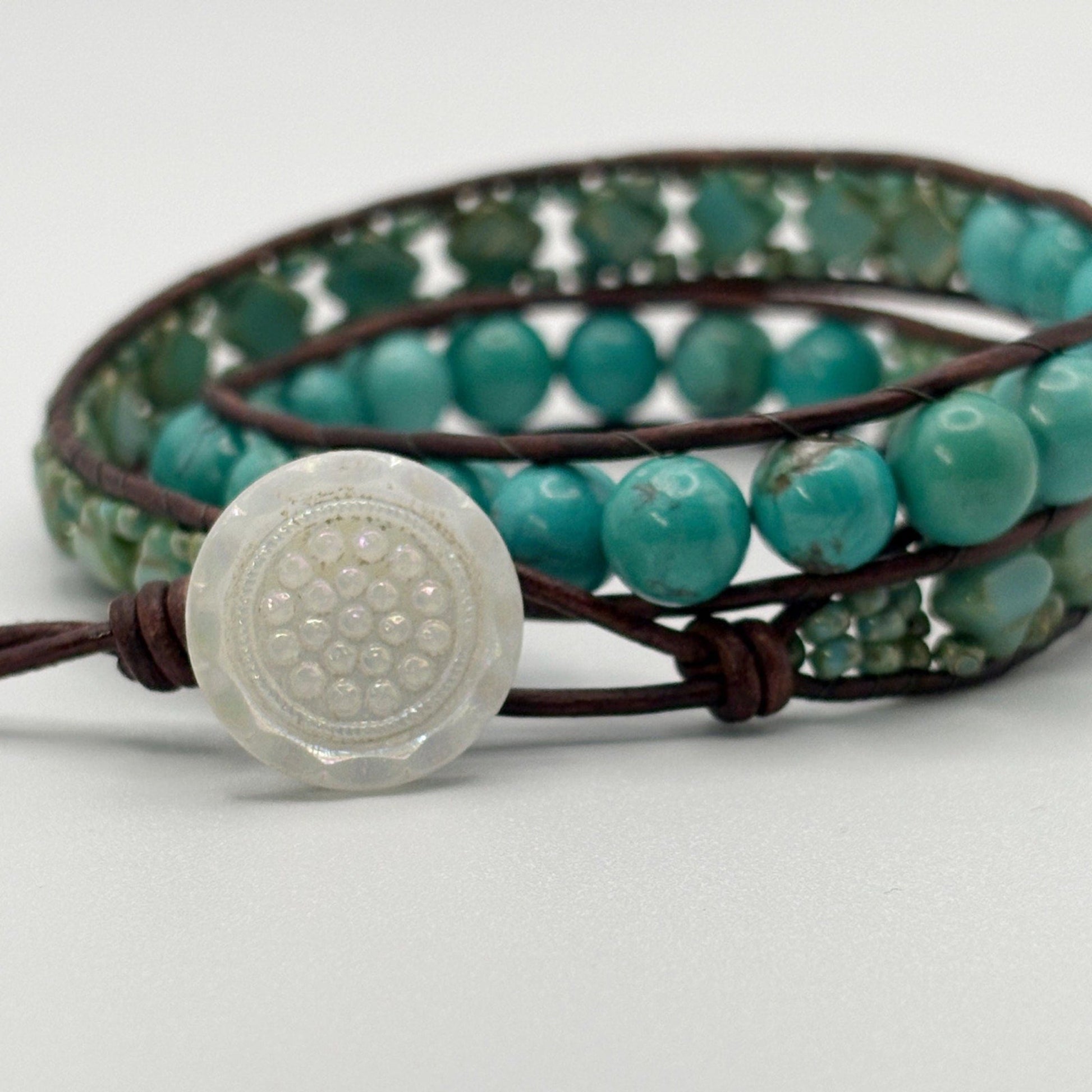 Turquoise beaded bracelet with a decorative button on a white background