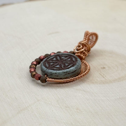 Pendant with etched glass and wirework on a textured surface