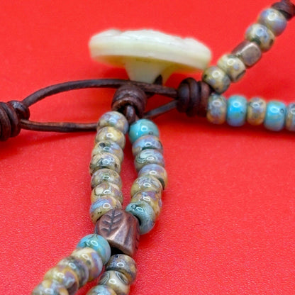 Close-up of a beaded bracelet with leaf-shaped beads on a red background