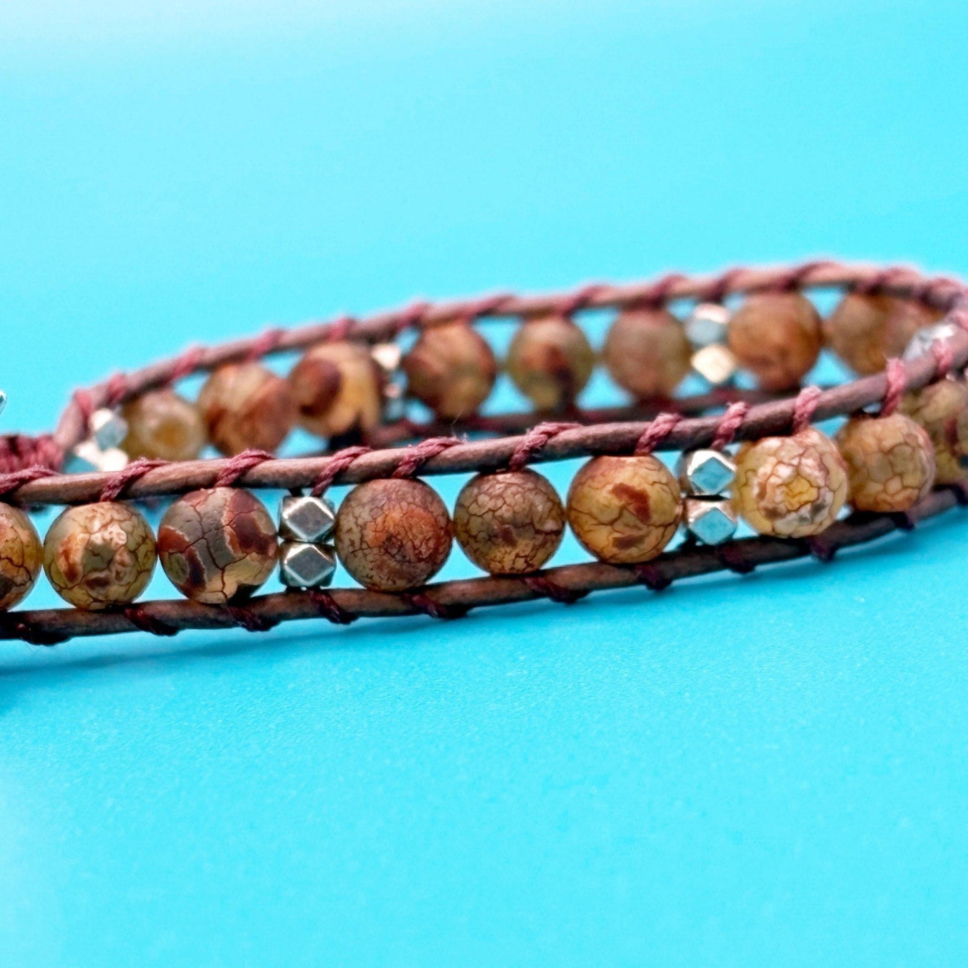 Bracelet with brown beads and pink leather strap on a blue background
