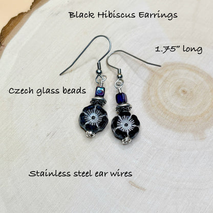 Black hibiscus earrings with Czech glass beads on a wooden surface
