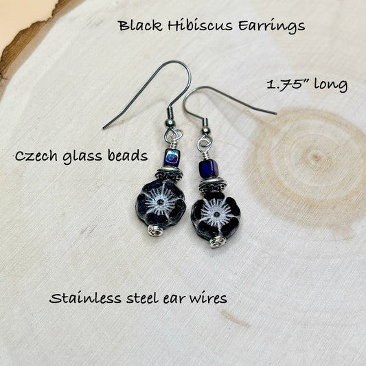 Black hibiscus earrings with Czech glass beads on a wooden surface