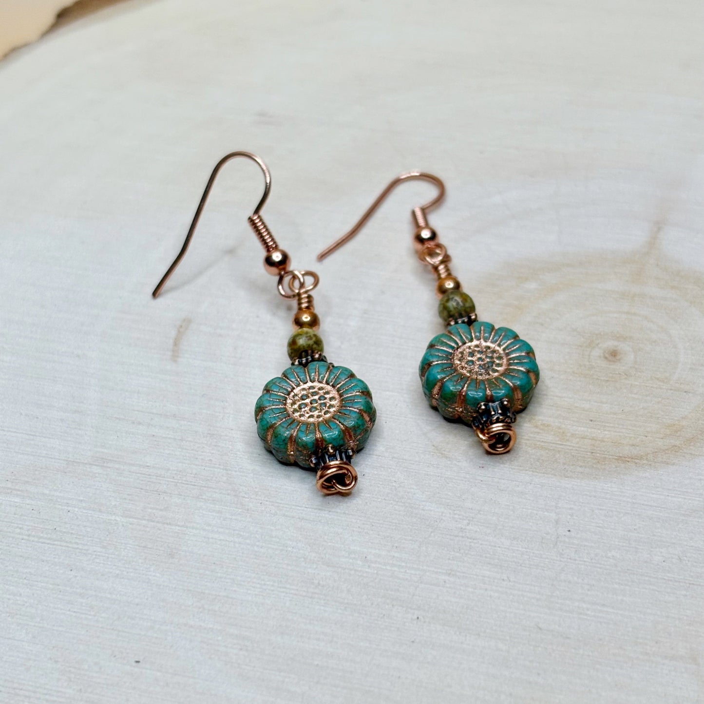 sunflower earrings with copper and teal embellished flowers on a wooden background