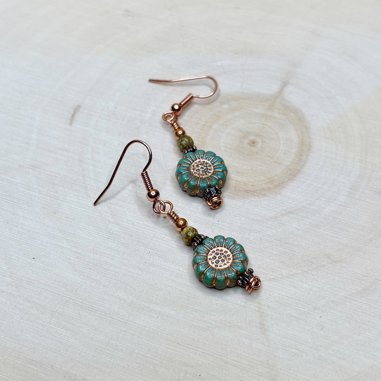 Floral beads with copper earrings on a wooden background
