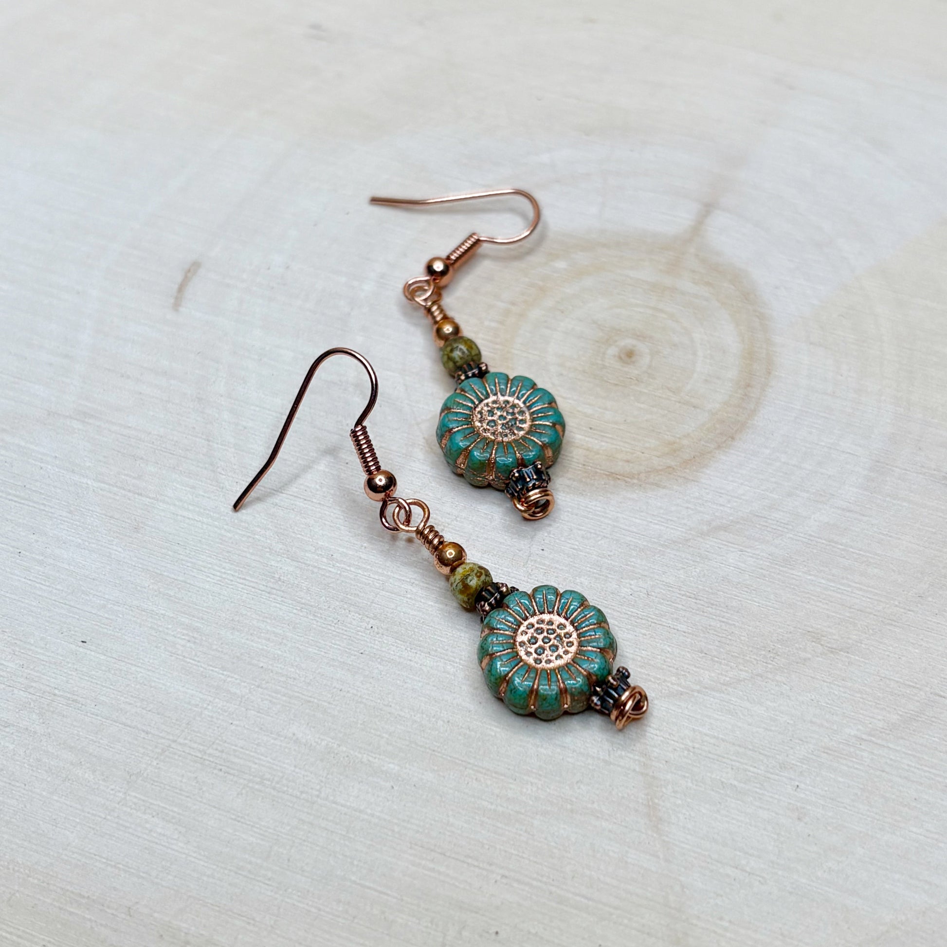 Floral beads with copper earrings on a wooden background