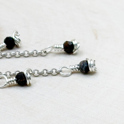 Silver chain with black beads on a white background