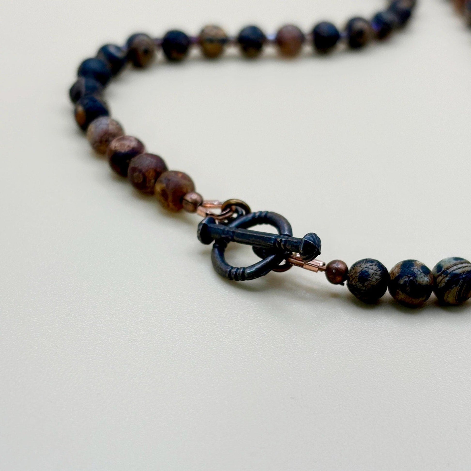 Necklace with dark beads and a clasp on a light background