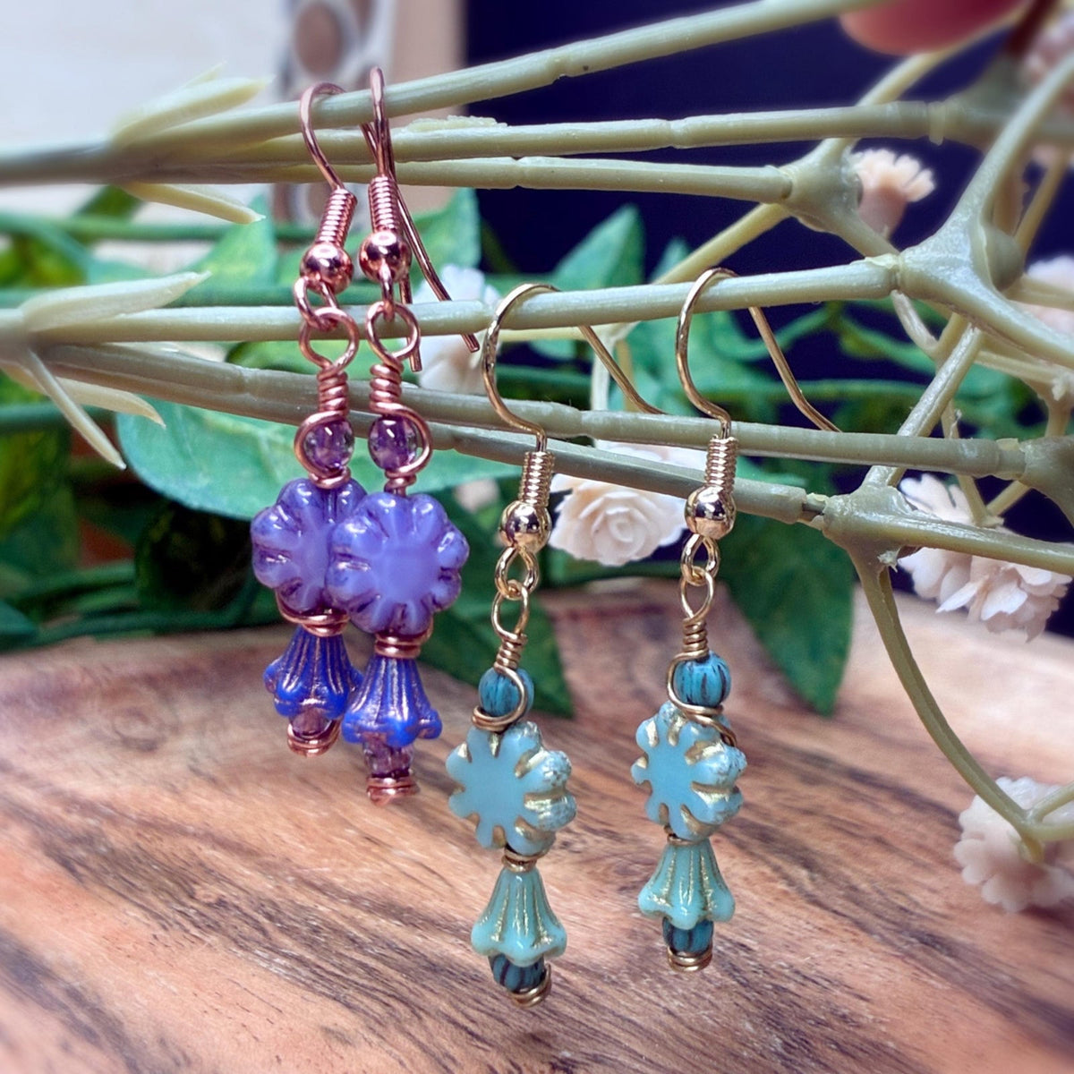 Purple cactus shape and turquoise cactus shape earrings hanging on a branch
