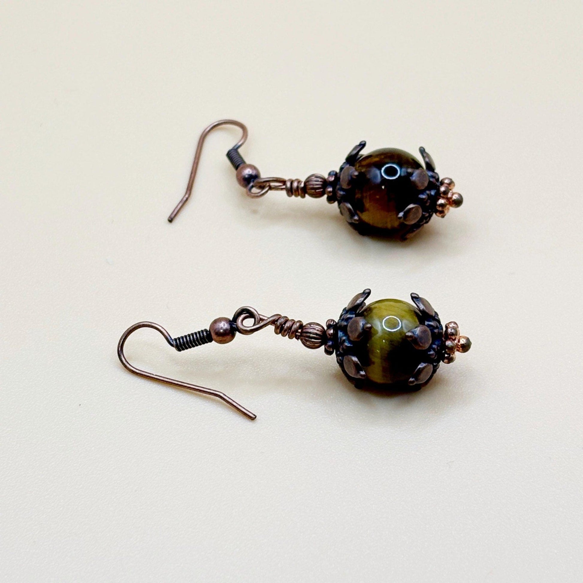 Pair of brown and copper beaded earrings on a beige background