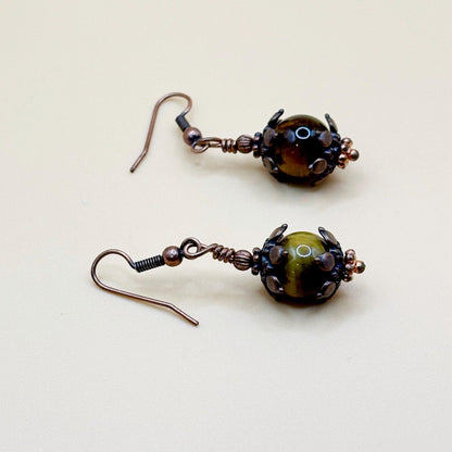 Pair of brown and copper beaded earrings on a beige background