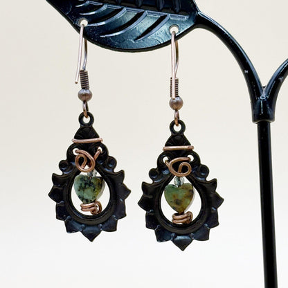 Pair of earrings with green heart-shaped stones on a white background