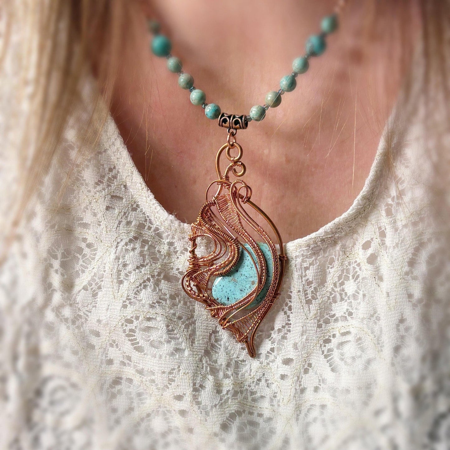 Necklace with a decorative pendant worn by a person against a neutral background