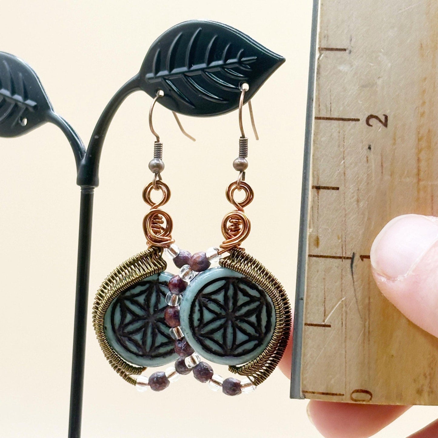 Decorative earrings on a stand with a ruler for scale