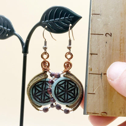 Decorative earrings on a stand with a ruler for scale