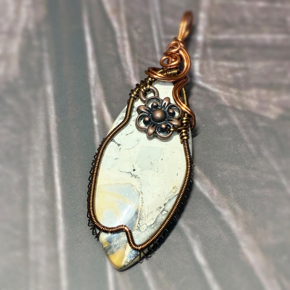 Handmade wire wrap pendant sitting on a dark background