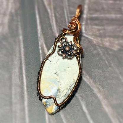 Handmade wire wrap pendant sitting on a dark background