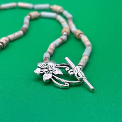 Necklace with floral pendant and toggle clasp on a green background