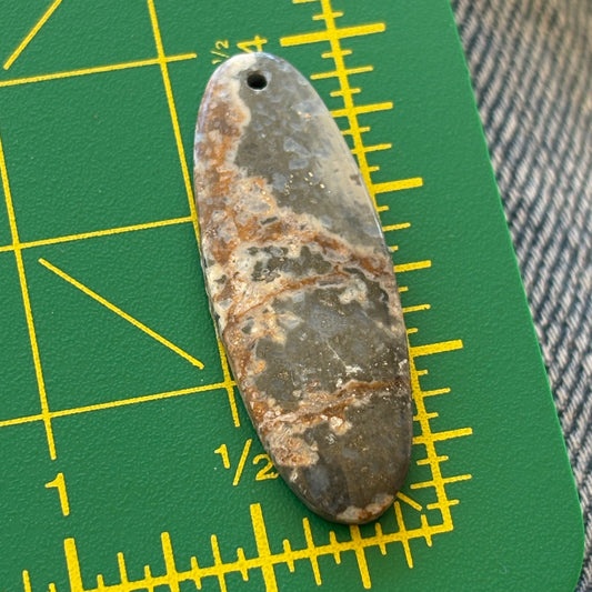 Rust-colored stone on a green cutting mat with yellow measurements