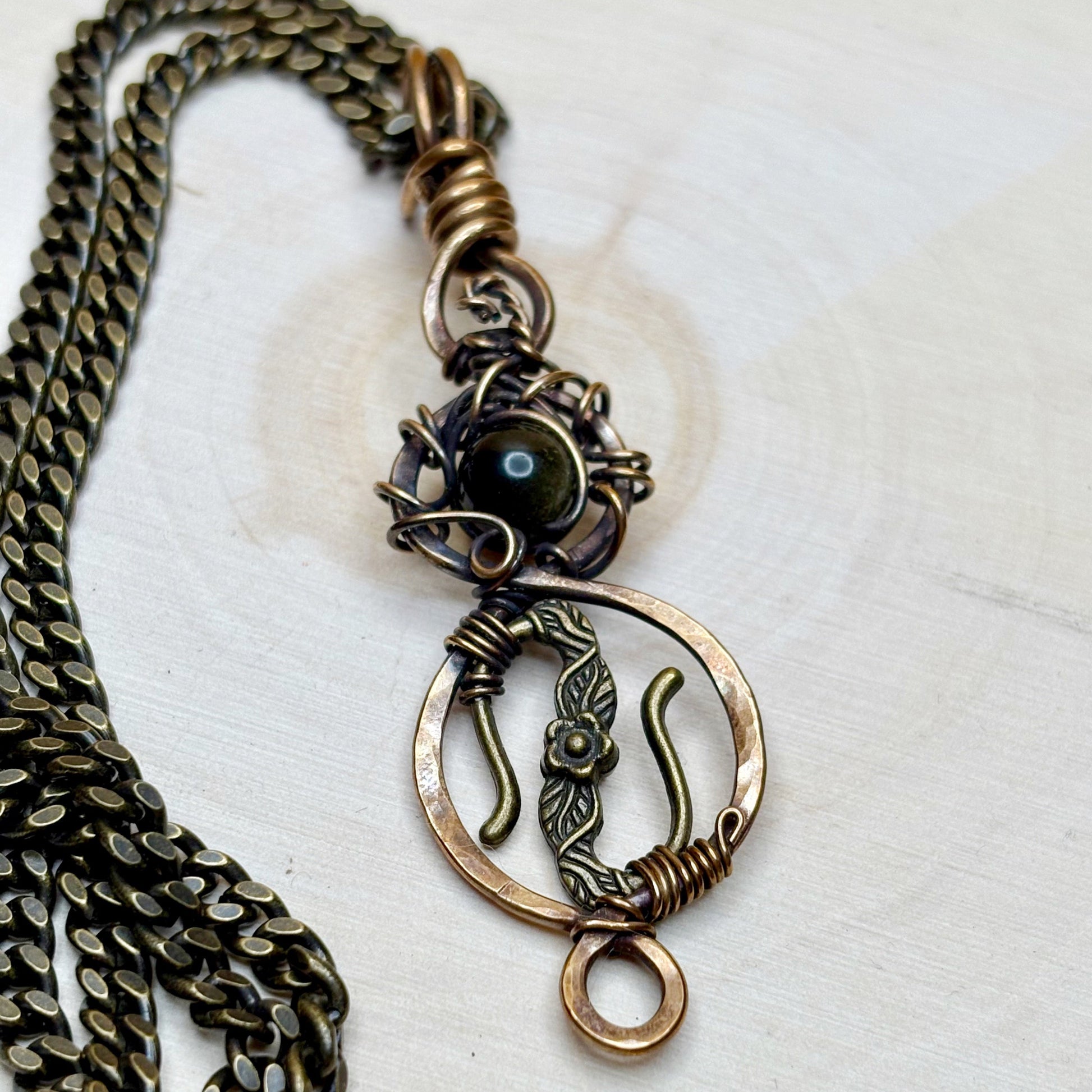 Bronze necklace with intricate pendant on a white background