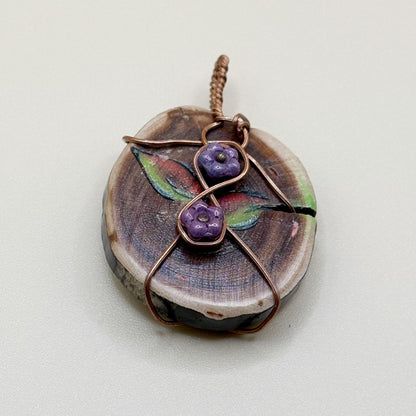 Handmade pendant with floral design and copper wire on a light gray background