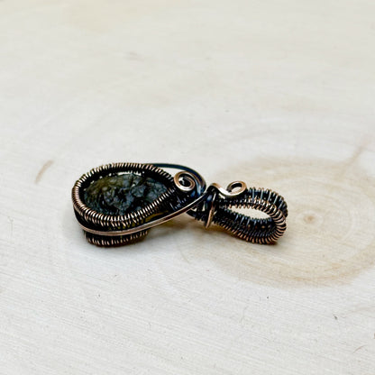 Jewelry pendant with a Moldavite tektite on a textured white surface