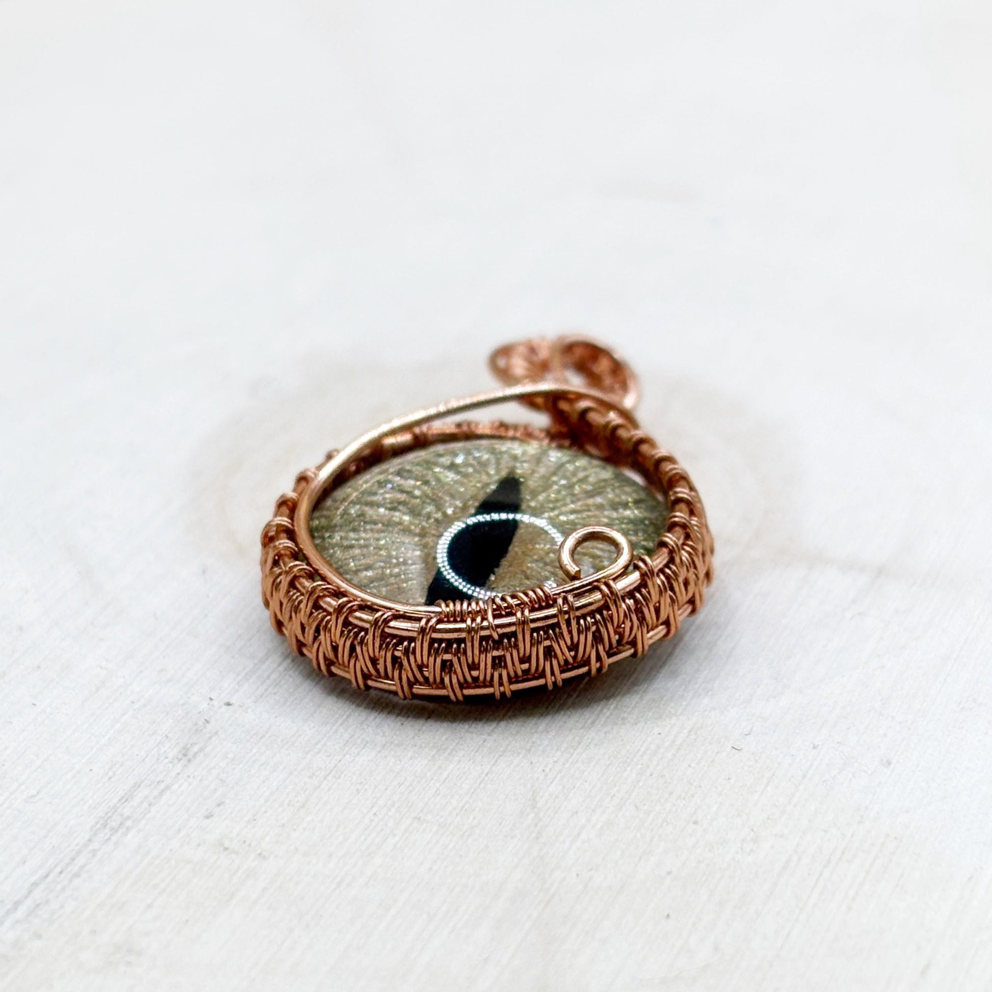 Copper pendant with a circular design on a white wooden background