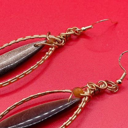 Earrings with feather-like pendants on a red background