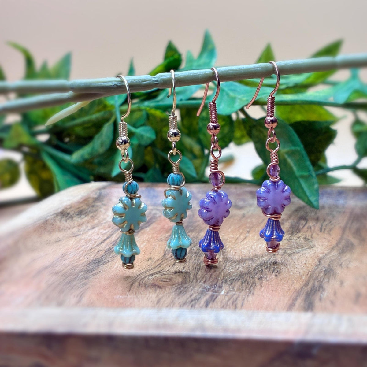 Earrings hanging on a branch showing floral beads in unique wire wrapping
