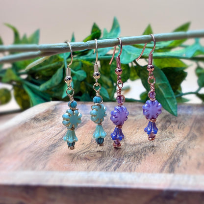 Earrings hanging on a branch showing floral beads in unique wire wrapping