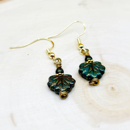 Pair of leaf-shaped earrings with gold accents on a white background