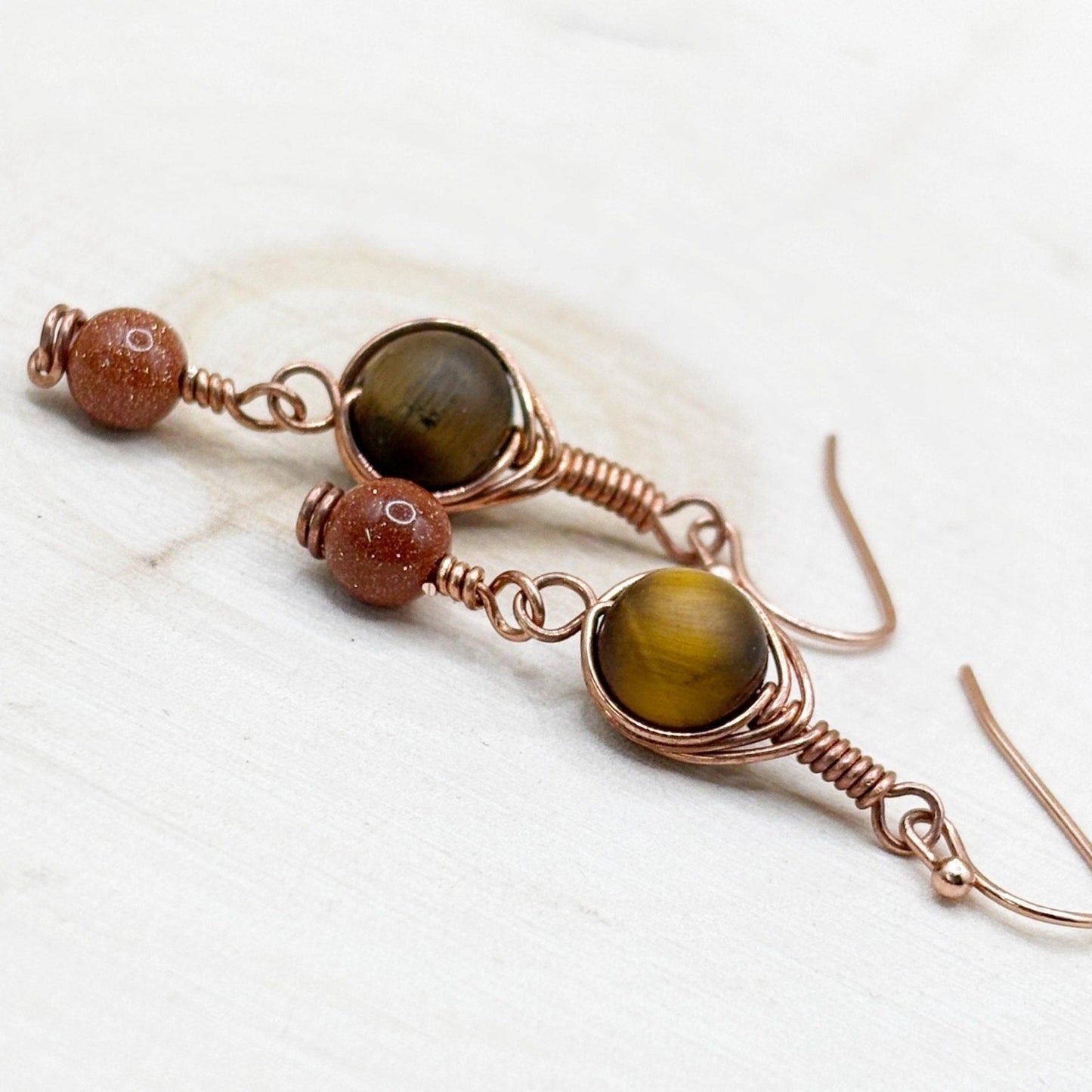 Pair of earrings with brown gemstones on a white wooden surface