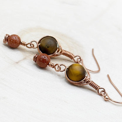 Pair of earrings with brown gemstones on a white wooden surface