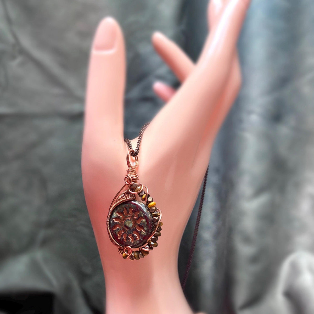 hand model showing the pendant dangling from a dainty copper chain
