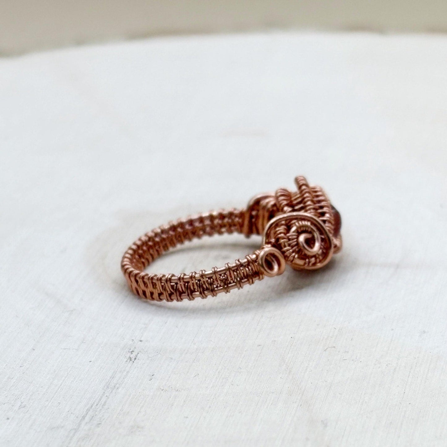 Copper wire-wrapped ring on a white fabric background