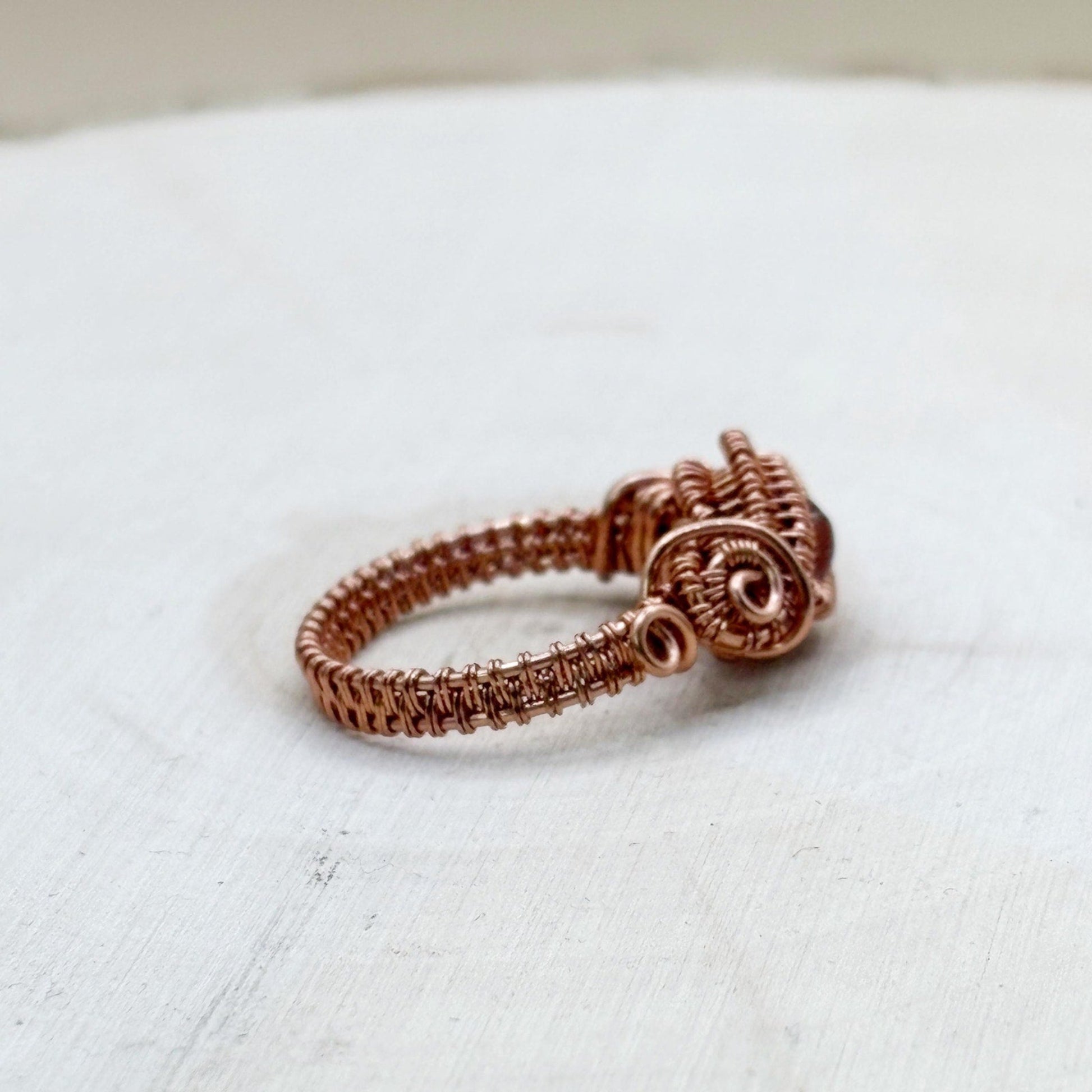 Copper wire-wrapped ring on a white fabric background