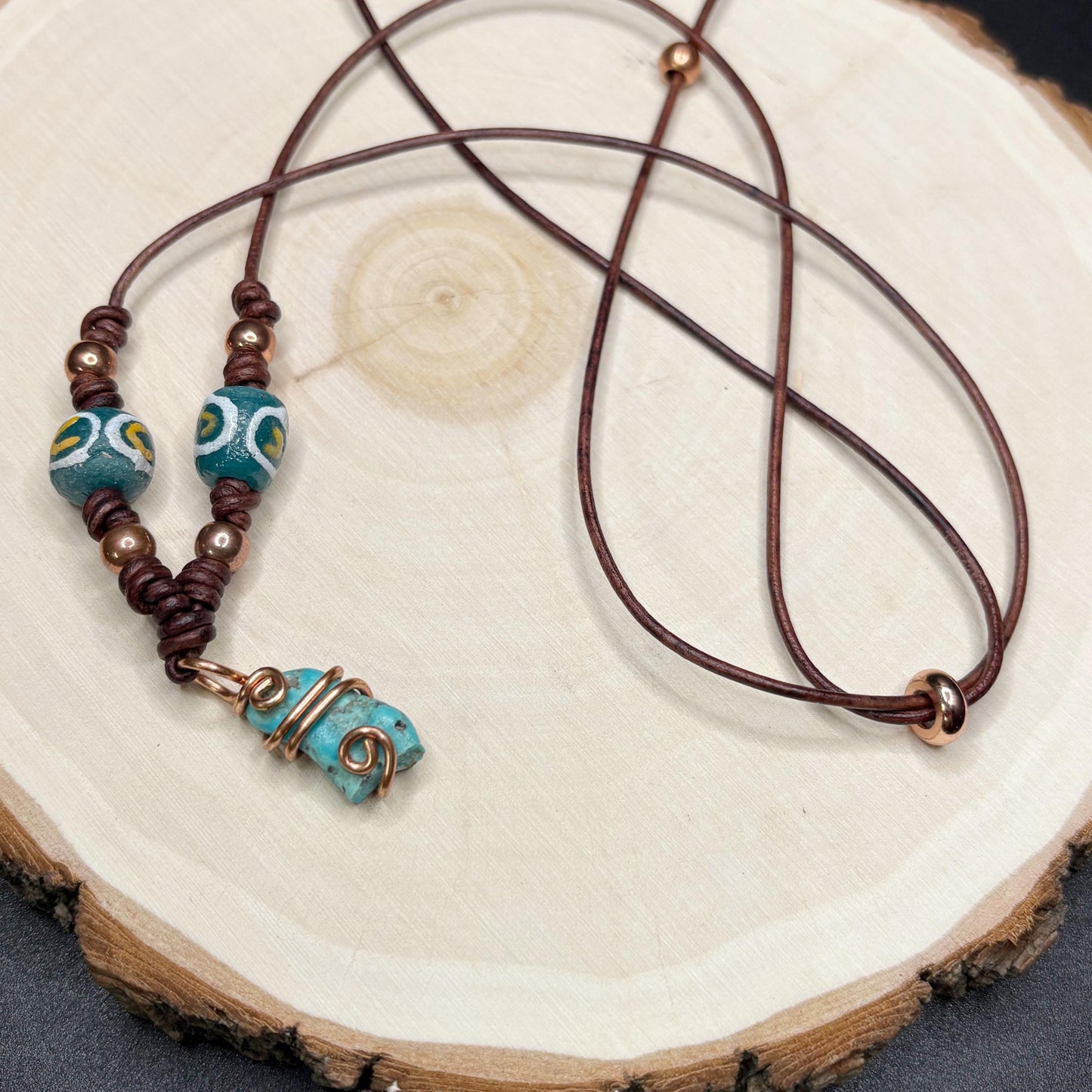 Necklace with turquoise beads and brown leather cord on a wooden surface
