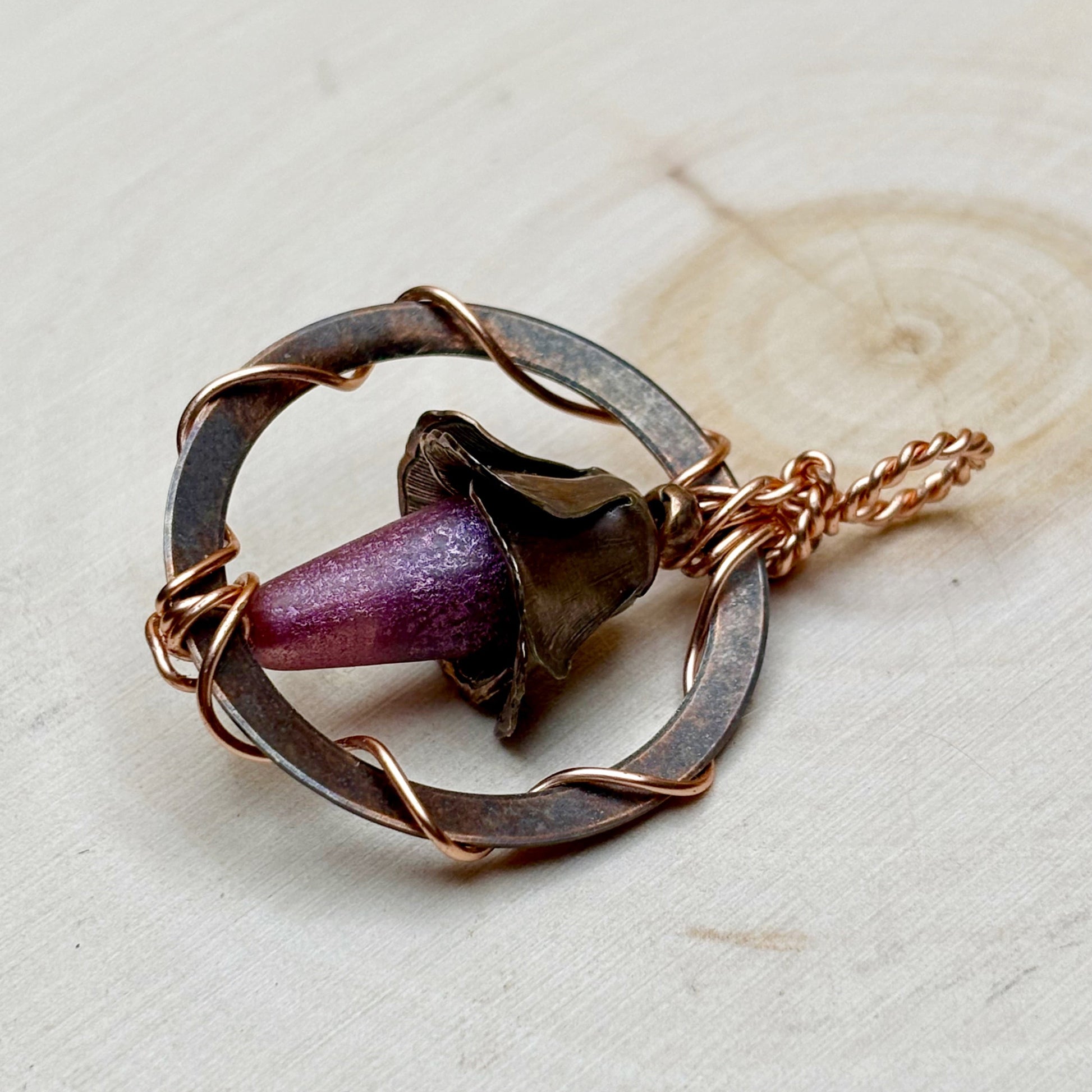 Necklace with a circular design and purple floral focal on a light background