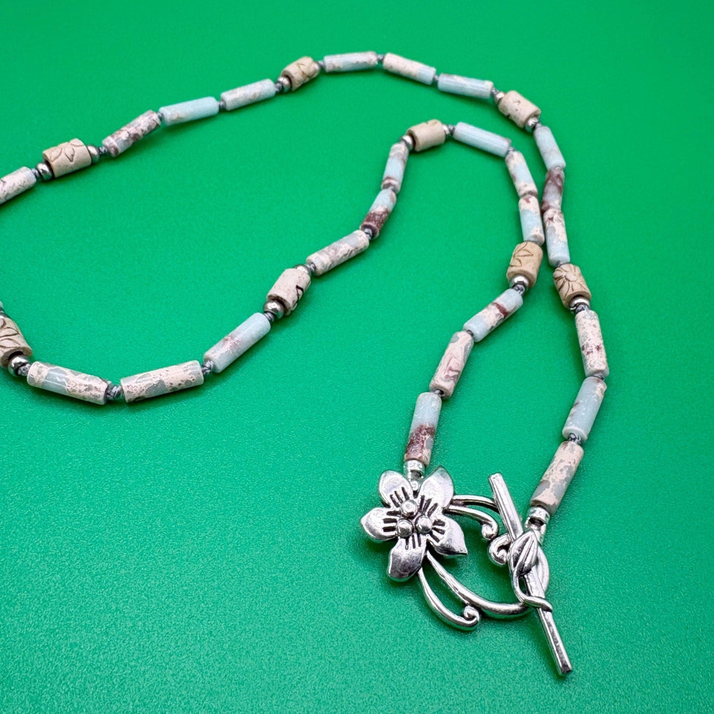 Necklace with floral pendant on a green background