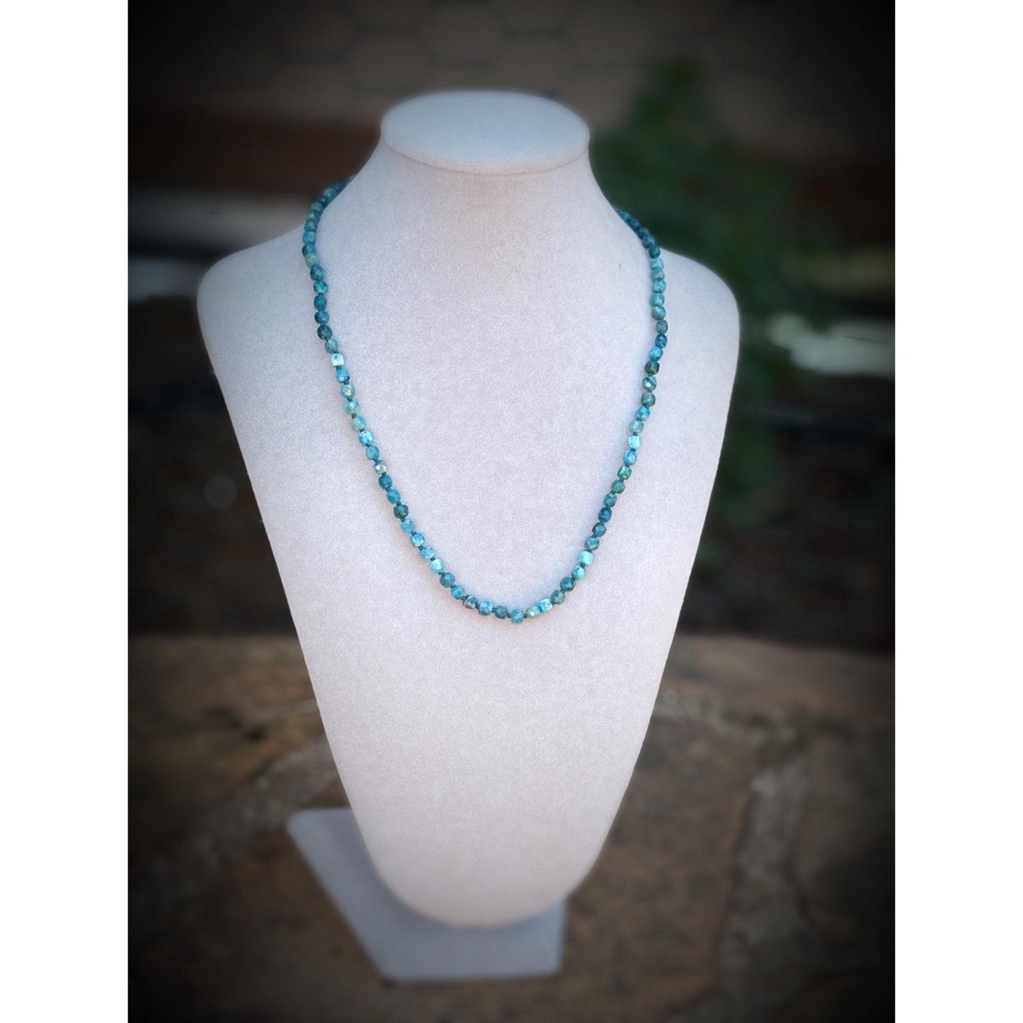 Blue beaded necklace on a mannequin bust with a blurred background