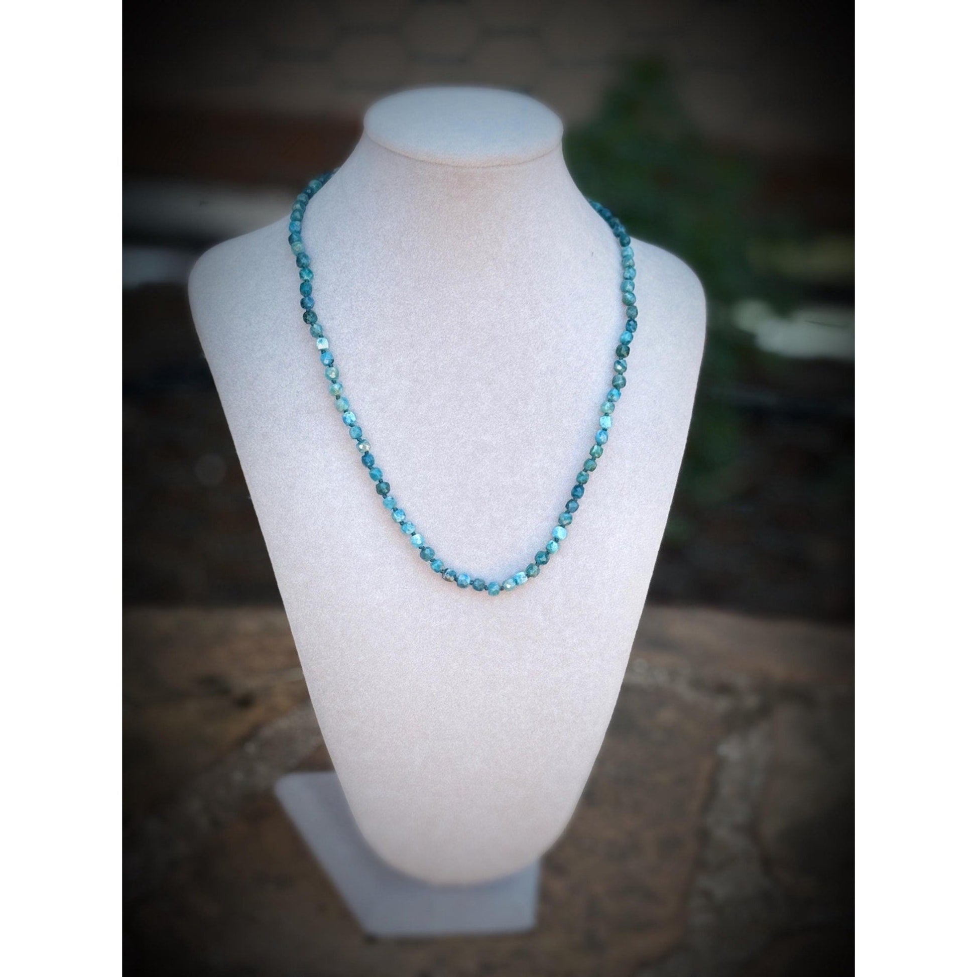 Blue beaded necklace on a mannequin bust with a blurred background
