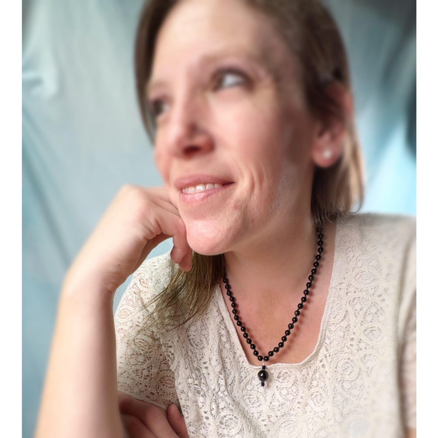 Woman wearing a black beaded necklace with a blurred background