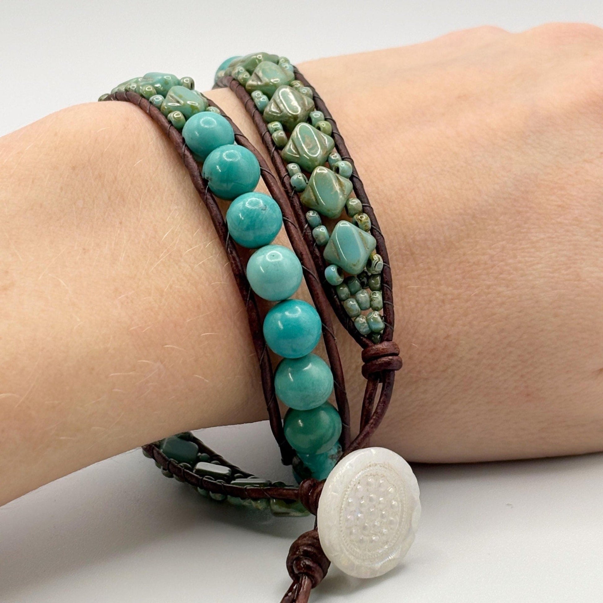 Turquoise beaded bracelet with brown leather strap on wrist against a white background